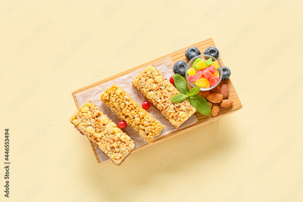 Board with healthy cereal bars, berries and nuts on color background