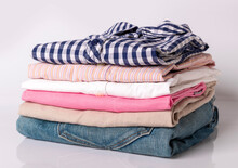 Close Up, Stack Of Folded Clothing. Pile Of Different Color Shirts, Sweaters And Other Garments Isolated On White Background With Copy Space.