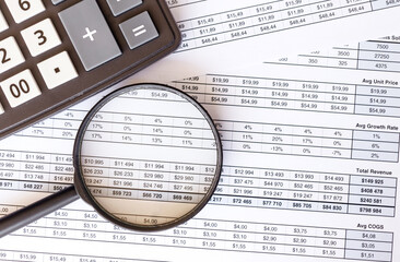 Calculator and magnifier with accounting and financial reporting on the table.