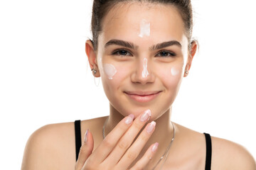 smiling teen girl applyes cosmetic product on her face