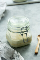 Wall Mural - Sourdough starter in a jar, yeast-free leaven starter for healthy organic rustic bread, home baking concept