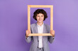 Photo of positive blogger schoolkid hold wooden frame make portrait wear grey suit isolated violet color background