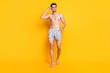 © deagreez - Photo of charming cute young guy shirtless dressed dark glasses smiling walking isolated yellow color background