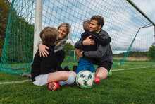 Delighted Sporty Family Giving Hugs In Football Field