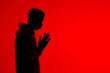 © ADDICTIVE STOCK - Anonymous black man praying with clasped hands on red background