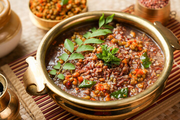 Ayurvedic porridge, Karkidaka Kanji herbal gruel in brass golden bowl Kerala South India. Ayurveda diet health drink for immunity, cleanse the body. Top view medicinal rice porridge Indian veg food