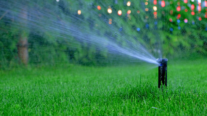 Automatic garden irrigation system watering lawn. Savings of water from sprinkler irrigation system with adjustable head. Automation for lawn irrigation, gardening, soccer fields or golf courses.Bokeh