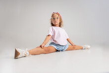 Portrait Of Little Preschool Caucasian Girl In Casual Clothes Sitting In Twine Isolated Over White Studio Background.