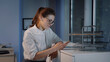 © nimito - Happy young businesswoman using mobile phone standing by window in office