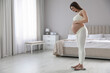 © New Africa - Pregnant woman standing on scales in bedroom. Space for text