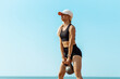 Sportswoman in sportswear lifting weights, Sportive woman holding a kettlebell during crossfit workout, on the beach