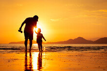Silhouette Of A Father And Son Walking On The Beach