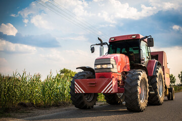 Poster - A farmer driving a big tractor to a corn field.