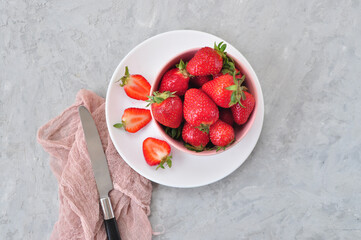 Wall Mural - Flat lay of fresh ripe sweet strawberries in a white bowl on a gray color background.