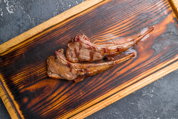 Wall Mural - Rack of lamb on old wooden board on dark stone table top view