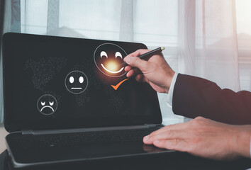 A man uses the laptop and chooses a face smile emoticon to show on the virtual screen. The survey, poll, or questionnaire for user experience or customer satisfaction research. The concept is Customer