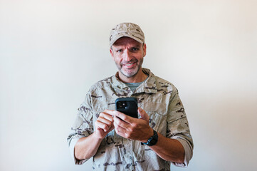 Canvas Print - Caucasian man in camouflaged army uniform using a smart phone, technology concept.