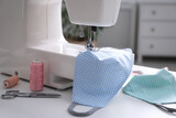 Fototapeta Do akwarium - Sewing machine with cloth mask on white table indoors, closeup