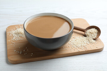 Tasty sesame paste and seeds on white wooden table