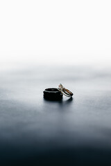 Sticker - Vertical shot of wedding rings of bride and groom on a gray surface