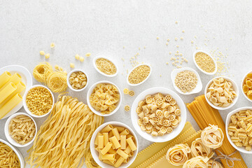 Poster - Pasta. Various kinds of uncooked pasta and noodles over stone background, top view with copy space for text. Italian food culinary concept. Collection of different raw pasta on cooking table