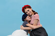 © Look! - Fashionable cheerful ladies with red hair in berets, bright t-shirts and modern skirts looking into camera and sitting on floor..