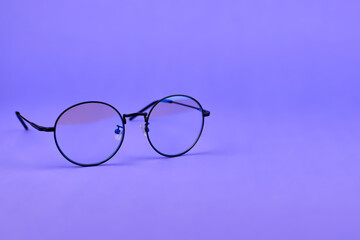 Round glasses on a purple background. Stylish glasses