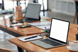 © NAMPIX - Mockup blank screen laptop computer and supplies on wooden table in co-workspace.