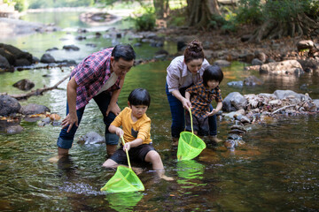 Asian family and two son fishing with fishing net in river