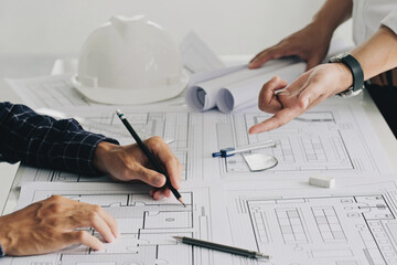 Two business man construction site engineers. working drawing on blueprint and discussing the floor plans over blueprint architectural plans at table in a modern office. construction concept