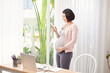 © makistock - pregnant asian woman working from home in modern office contacting using mobile phone in call talking,