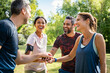 © Rido - Group of active mature friends in park stacking hands after workout