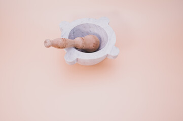 Sticker - Marble mortar with wooden pestle on a peach background with free space for text