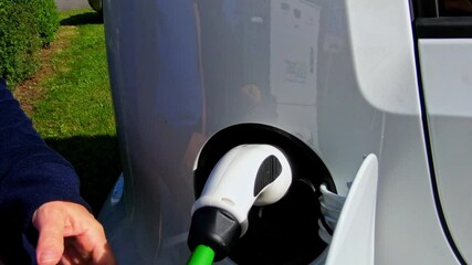 Poster - A closeup view of a male hand switching white electric vehicle to charging in HD