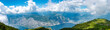 Panorama einer Bergkette mit saftigen Wiesen, massiven Felsen und dem Gardasee.