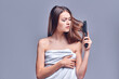 © Olena Apetroaiei - Hair problem - unhappy young woman combing her hair isolated on gray background. Hair loss, shedding.