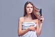 © Olena Apetroaiei - Hair problem - unhappy young woman combing her hair isolated on gray background. Hair loss, shedding.