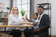 © sofiko14 - Pleasant caucasian pediatrician greeting little patient with high five at cabinet. African american father sitting at table with pretty daughter on knees. Regular checkup for children.