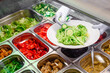 Showcase salad bar with an assortment of ingredients for healthy and dietary food. Salad making process. High quality photo