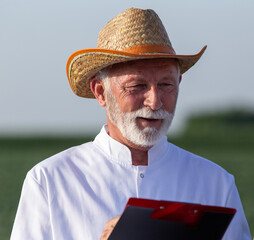 Poster - Portrait of elderly male agronomist wearing straw hat holding clipboard.