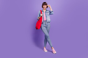 Canvas Print - Full length photo of nice millennial brunette lady hold bag wear spectacles jeans shirt sneakers isolated on purple background