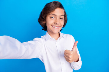 Sticker - Photo of charming pretty schoolboy wear formal clothes tacking selfie showing thumb up smiling isolated blue color background