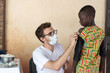 Young white volunteer preparing a small African boy to get a vaccine shot during childhood disease prevention