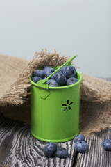 Wall Mural - Blueberries in a metal bucket. Linen fabric. On pine boards. Close-up shot.