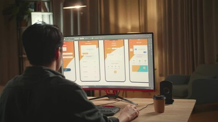 Asian Male Mobile Application Developer Works With Graphics On His Personal Computer. He Works At Night
