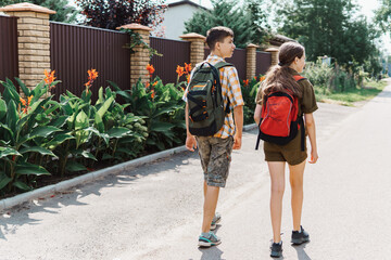 two teenagers boy and girl going down the street to school, education and back to school concept