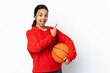 © luismolinero - Young woman playing basketball over isolated white background surprised and pointing side