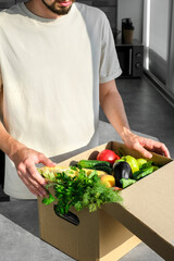 man ordered food delivery to his home. a man unpacks an online order of vegetables and fruits from an online store. fast delivery of fresh products. Food for vegetarian and vegan