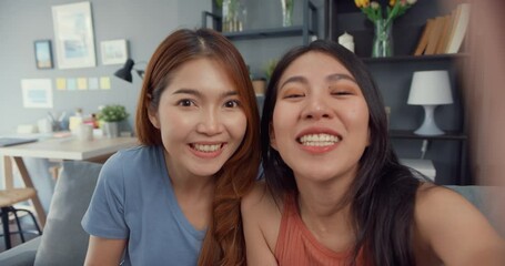 Wall Mural - Teenager Asian women feeling happy smiling selfie and looking to camera while relax in living room at home. Cheerful Roommate ladies video call with friend and family, Lifestyle woman at home concept.