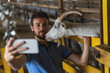 © Cavan Images - guy takes a selfie on the phone with a goat